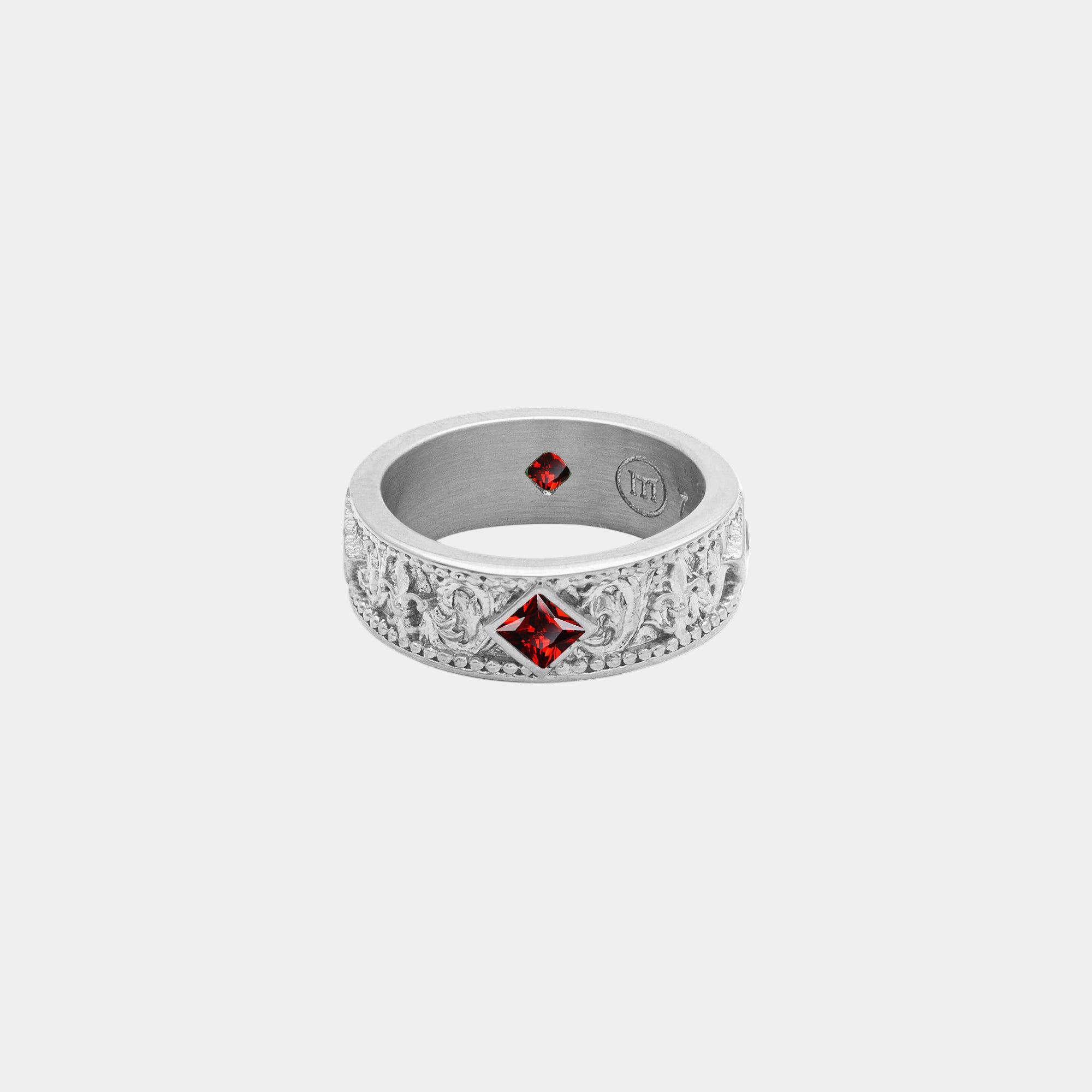 Silver ring with red gemstones on a white background
