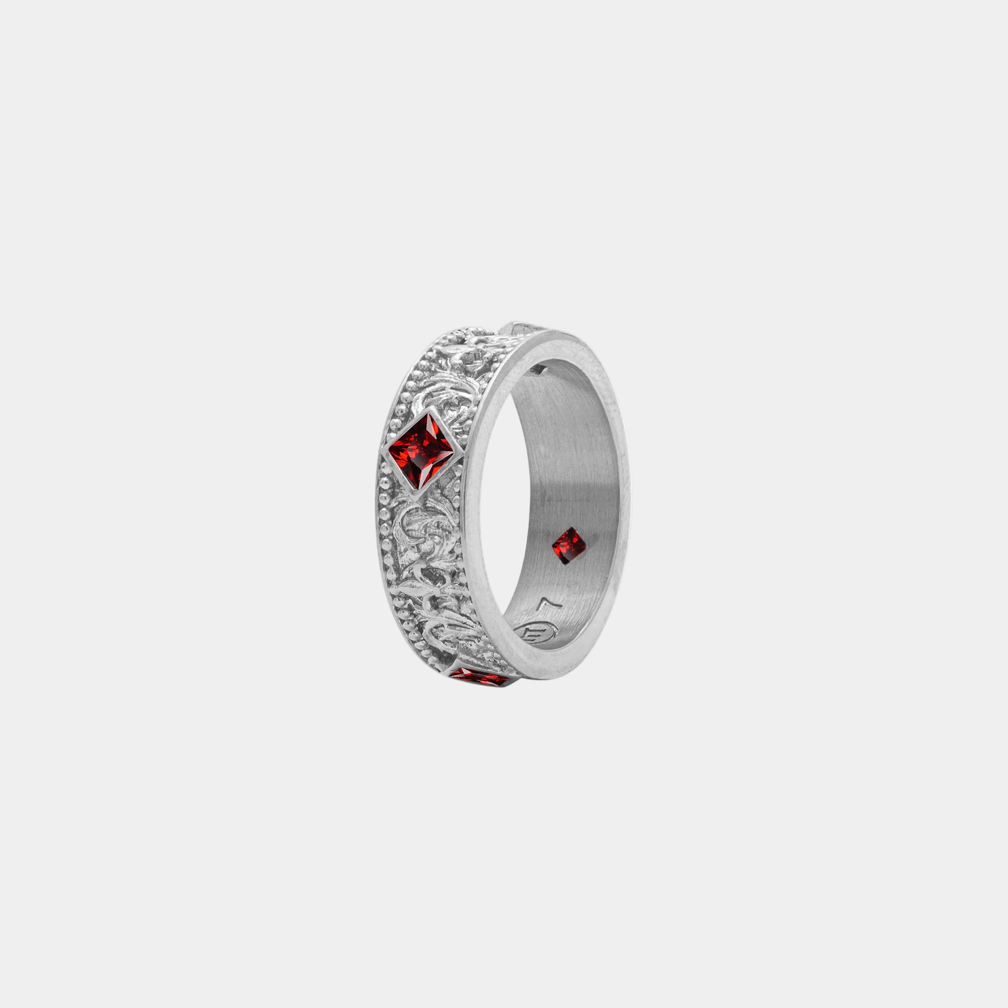 Silver ring with red gemstones on a white background